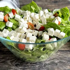 Sałatka z kostkami tofu, która smakuje jak feta. Zielona sałata, pomidorki koktajlowe i tofu w szklanej misie.