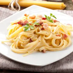Pyszne spaghetti carbonara, przygotowane według oryginalnego przepisu, z chrupiącym boczkiem i świeżą natką pietruszki.