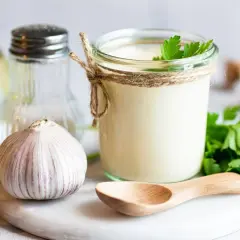 Sos aioli w słoiku, czosnek, cytryna i zioła. Różnica między sosem aioli a klasycznym majonezem czosnkowym jest subtelna, ale wyczuwalna.