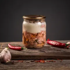 Słoik z mięsnym sosem do spaghetti, obok papryczki chili i czosnku. Czy można zawekować sos do spaghetti z mięsem? Tak, to świetny sposób na jego przechowywanie.