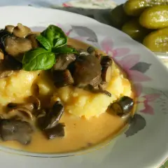 Pyszny ziemniaczany purée z sosem z opieniek, udekorowany bazylią. Idealny przepis, jak zrobić sos z opieniek.