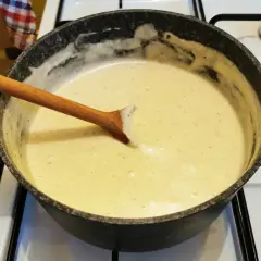 Kremowy sos na patelni, z drewnianą łyżką. Różnica między sosem beszamelowym a velouté w bazie i smaku jest subtelna, ale wyczuwalna.