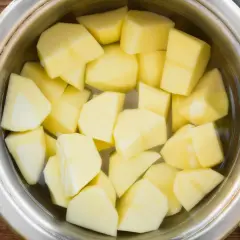 Pokrojone ziemniaki w garnku z wodą, gotowe do przygotowania idealnej sałatki. Czas gotowania ziemniaków na sałatkę jest kluczowy.