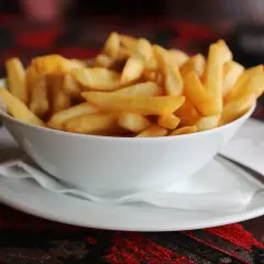 Chrupiące frytki domowe jak z restauracji krok po kroku. Złociste, idealne ziemniaczki w białej miseczce.