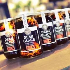 Słoiki z sosem demi-glace, jak zrobić idealny sos demi-glace bez 48 godzin gotowania. Płomienie sugerują intensywny smak.