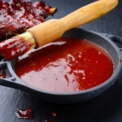 Pędzel zanurzony w sosie barbecue, gotowy do posmarowania żeber. Idealny przepis na to, jak zrobić sos barbecue.