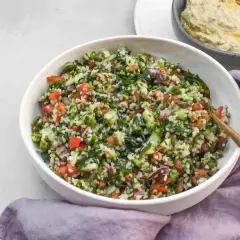 Kolorowa sałatka tabbouleh z komosą ryżową, pomidorami, ogórkiem i ziołami. Idealna alternatywa dla tradycyjnej wersji.