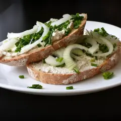 Dwa otwarte kanapki z pastą, cebulą i szczypiorkiem. Aby uniknąć mięknięcia grzanek w sałatce, podawaj je oddzielnie.