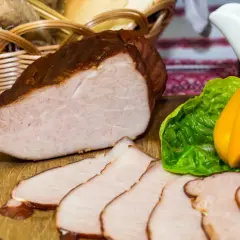 Gotowy do wędzenia schab, pokrojony w plastry, z dodatkiem warzyw i koszyka z pieczywem. Idealny przepis na to, jak przygotować schab do wędzenia.