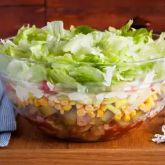 Warstwowa sałatka gyros w szklanej misie, z sałatą, kukurydzą i ogórkiem. Zastanawiasz się, ile sałatka gyros może stać w lodówce?