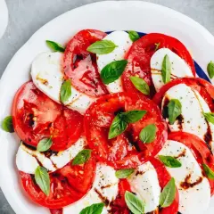 Sałatka caprese z pomidorami i mozzarellą. Woda w sałatce może pojawić się z powodu dojrzałości pomidorów lub nadmiaru sosu.
