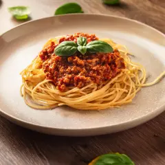 Pyszne spaghetti z sosem bolońskim, ozdobione bazylią. Idealny przykład, jak zrobić sos do spaghetti, który zachwyci każdego.