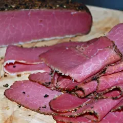 Domowe pastrami z mostka wołowego: oto jak przygotować je krok po kroku. Pokrojone plastry na desce.
