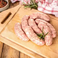 Surowa biała kiełbasa na desce, gotowa do przyrządzenia. Dowiedz się, jak długo gotować białą kiełbasę, by była idealna.