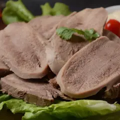 Plastry wieprzowych ozorów, gdzie są ślinianki, podane z sałatą i pomidorkami.