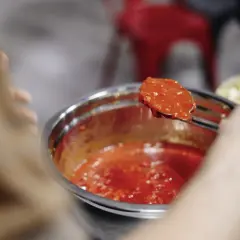 Łyżka z oryginalnym włoskim sosem do pizzy, gotowym do nałożenia na ciasto.