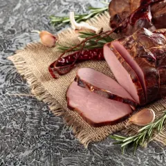 Wędzony schab, pokrojony w plastry, z czosnkiem, rozmarynem i papryczkami chili. Idealny przykład, jak zamarynować schab do wędzenia.