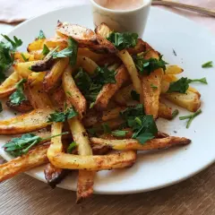 Złociste frytki z airfryera, posypane natką pietruszki. Idealne, gdy chcesz wiedzieć, jak zrobić frytki w airfryer.