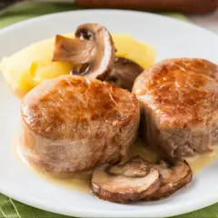 Dwa medaliony polędwicy wieprzowej z puree ziemniaczanym i pieczarkami. Idealna temperatura dla polędwicy wieprzowej to klucz do soczystości.