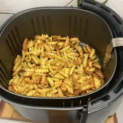Mnóstwo pysznych, pofalowanych frytek w frytkownicy beztłuszczowej, gotowych do podania.