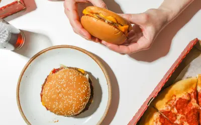 Jak dobrać mięso na domowe burgery? Zawartość tłuszczu a soczystość. Na stole burger, pizza i napój.