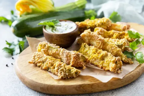 Chrupiące frytki z cukinii w panierce panko, podane z sosem. Idealna przekąska, która udowadnia, że frytki z cukinii można zrobić w panierce panko.