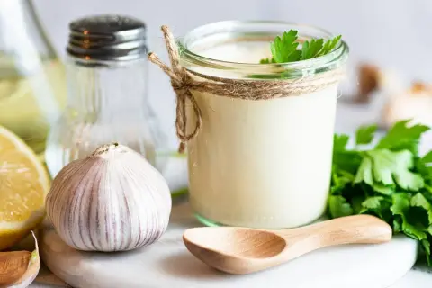 Sos aioli w słoiku, czosnek, cytryna i zioła. Różnica między sosem aioli a klasycznym majonezem czosnkowym jest subtelna, ale wyczuwalna.