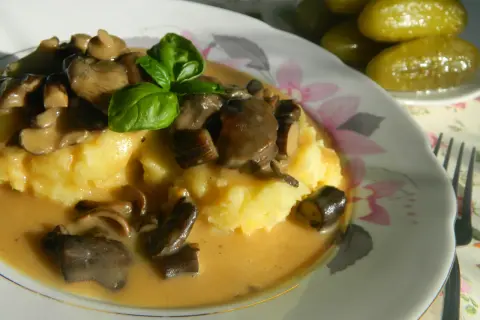 Pyszny ziemniaczany purée z sosem z opieniek, udekorowany bazylią. Idealny przepis, jak zrobić sos z opieniek.