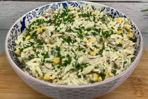 Pyszna sałatka z tuńczykiem i makaronem orzo, z kukurydzą i szczypiorkiem, w ozdobnej misce.