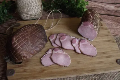 Jak zrobić soczysty schab wędzony? Na desce leżą dwa wędzone kawałki schabu, jeden w całości, drugi pokrojony w plastry.