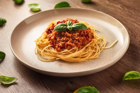 Pyszne spaghetti z sosem bolońskim, ozdobione bazylią. Idealny przykład, jak zrobić sos do spaghetti, który zachwyci każdego.