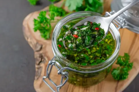 Sos chimichurri do mięsa z grilla przepis: świeża pietruszka, czosnek, chili i oliwa w słoiku. Idealny dodatek do grillowanych przysmaków.