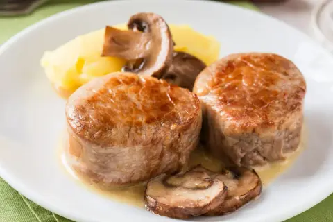 Dwa medaliony polędwicy wieprzowej z puree ziemniaczanym i pieczarkami. Idealna temperatura dla polędwicy wieprzowej to klucz do soczystości.