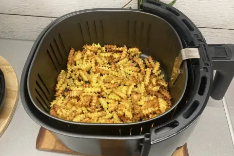 Mnóstwo pysznych, pofalowanych frytek w frytkownicy beztłuszczowej, gotowych do podania.