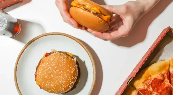Jak dobrać mięso na domowe burgery? Zawartość tłuszczu a soczystość. Na stole burger, pizza i napój.