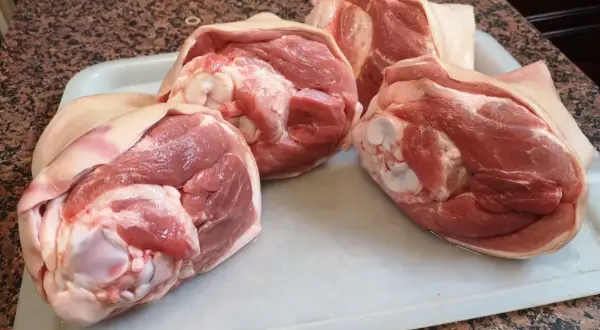 Surowe golonki wieprzowe na tacy, gotowe, by dowiedzieć się, ile piec golonkę w piekarniku.