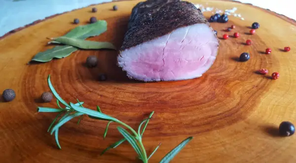 Idealnie różowe polędwiczki wieprzowe, idealne do przygotowania metodą sous-vide w domu. Zioła i pieprz dopełniają danie.