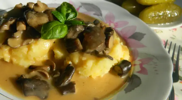 Pyszny ziemniaczany purée z sosem z opieniek, udekorowany bazylią. Idealny przepis, jak zrobić sos z opieniek.