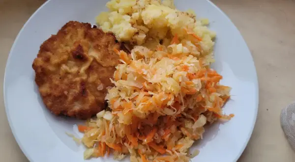 Złocisty kotlet schabowy z ziemniakami i surówką z kapusty i marchewki – idealne połączenie, co pasuje do schabowego.