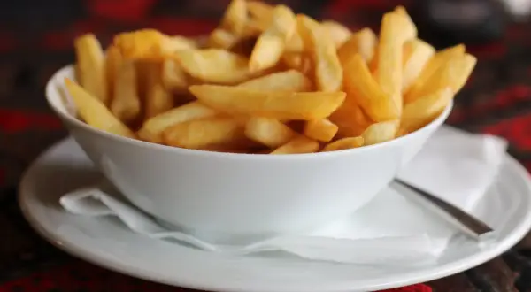 Chrupiące frytki domowe jak z restauracji krok po kroku. Złociste, idealne ziemniaczki w białej miseczce.