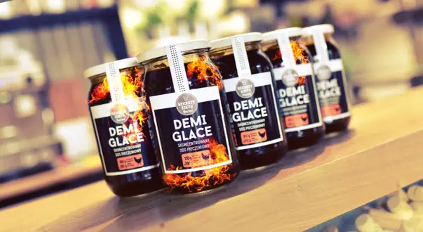 Słoiki z sosem demi-glace, jak zrobić idealny sos demi-glace bez 48 godzin gotowania. Płomienie sugerują intensywny smak.