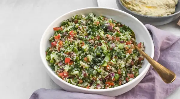 Kolorowa sałatka tabbouleh z komosą ryżową, pomidorami, ogórkiem i ziołami. Idealna alternatywa dla tradycyjnej wersji.