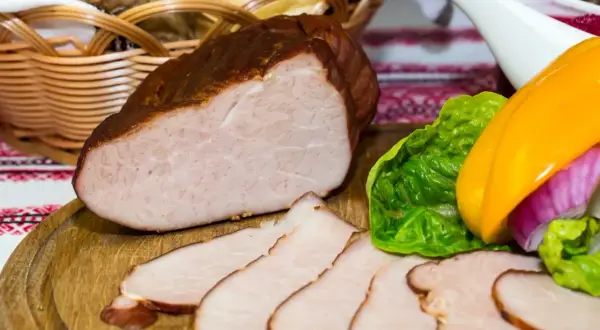 Gotowy do wędzenia schab, pokrojony w plastry, z dodatkiem warzyw i koszyka z pieczywem. Idealny przepis na to, jak przygotować schab do wędzenia.