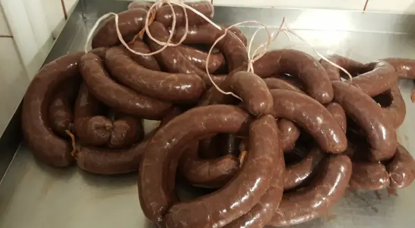 Kaszanka, pyszna i tradycyjna, idealna dla dzieci. Wiele krążków świeżej kaszanki na metalowej tacy.