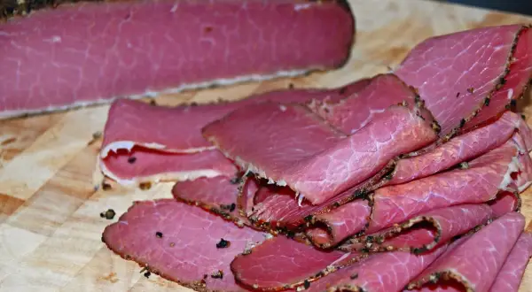 Domowe pastrami z mostka wołowego: oto jak przygotować je krok po kroku. Pokrojone plastry na desce.