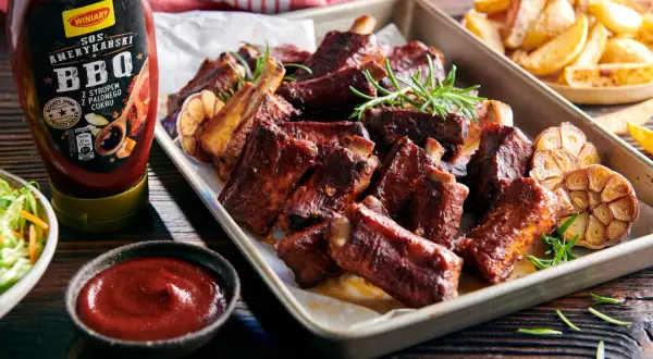 Soczyste żeberka BBQ z czosnkiem i rozmarynem, idealnie pasują do żeberek, a obok sos i frytki.