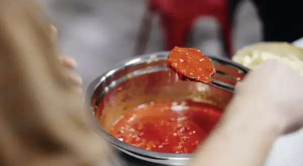 Łyżka z oryginalnym włoskim sosem do pizzy, gotowym do nałożenia na ciasto.