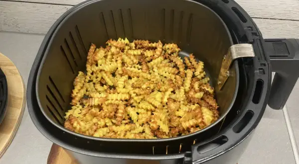 Mnóstwo pysznych, pofalowanych frytek w frytkownicy beztłuszczowej, gotowych do podania.