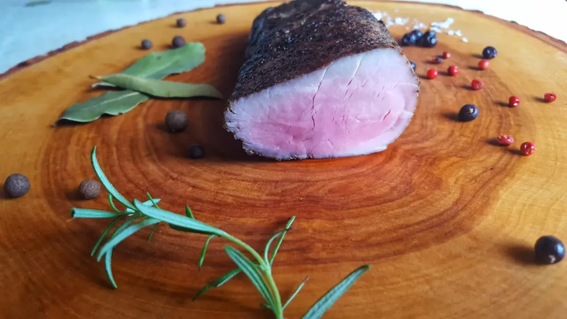 Idealnie różowe polędwiczki wieprzowe, idealne do przygotowania metodą sous-vide w domu. Zioła i pieprz dopełniają danie.