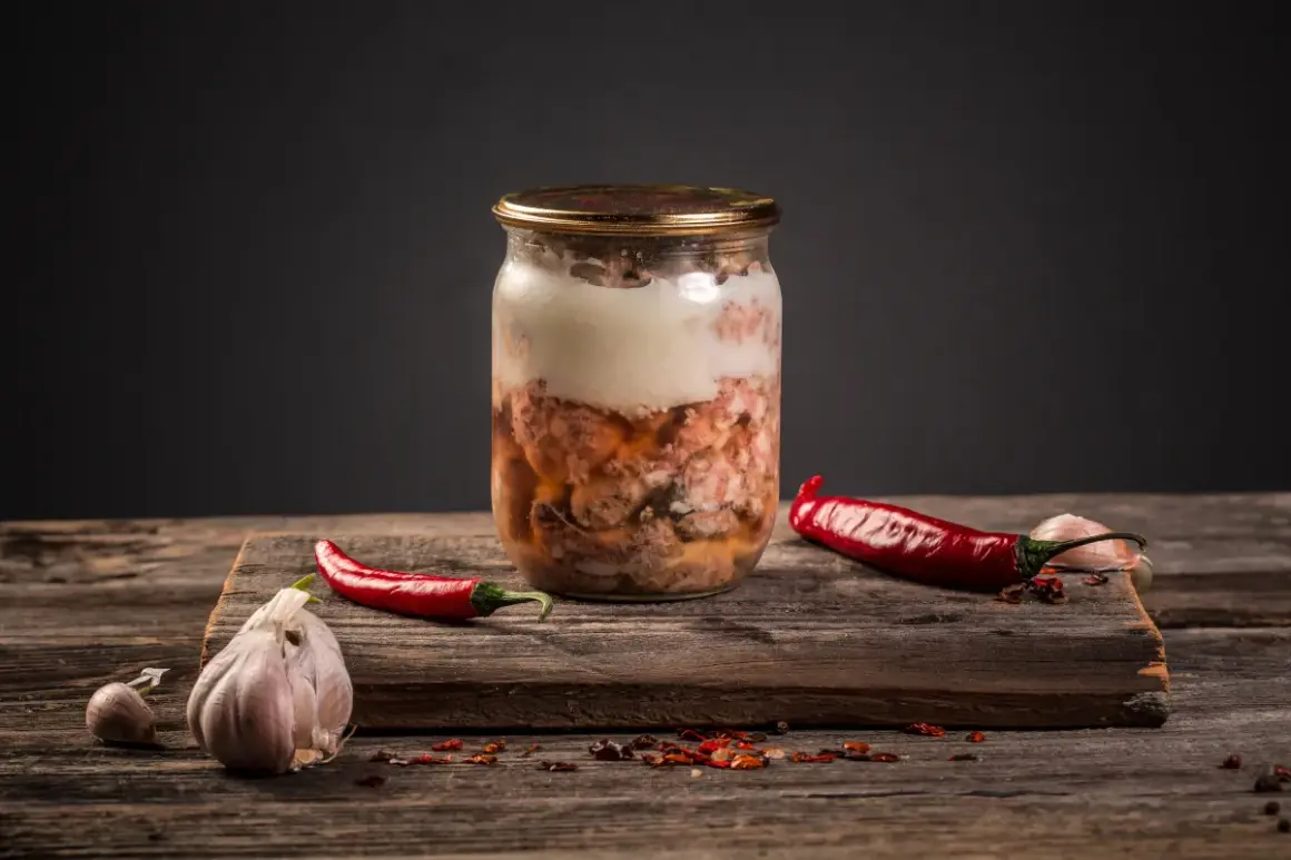 Słoik z mięsnym sosem do spaghetti, obok papryczki chili i czosnku. Czy można zawekować sos do spaghetti z mięsem? Tak, to świetny sposób na jego przechowywanie.